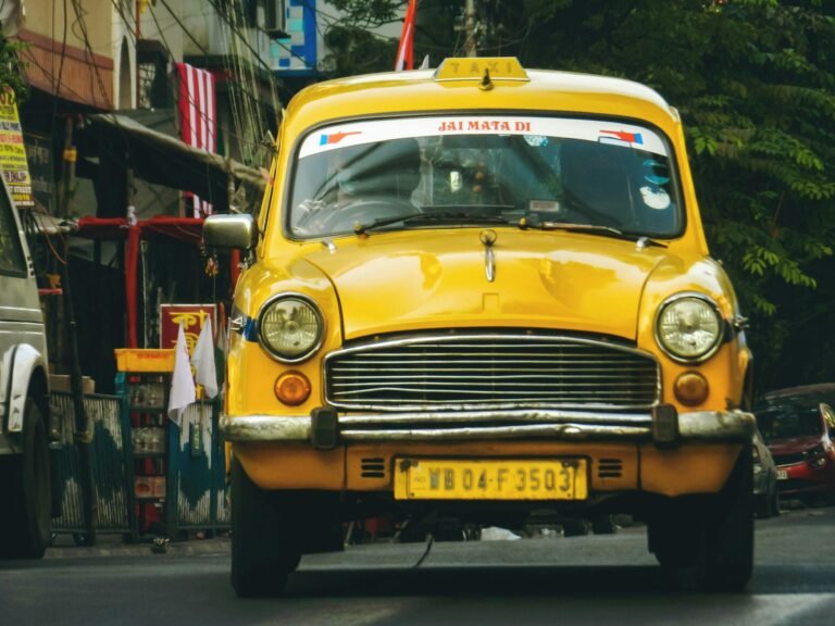 Classic yellow taxi driving through the vibrant streets of Kolkata, India.